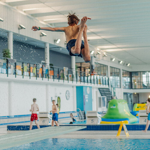 Gutt som hopper i basseng